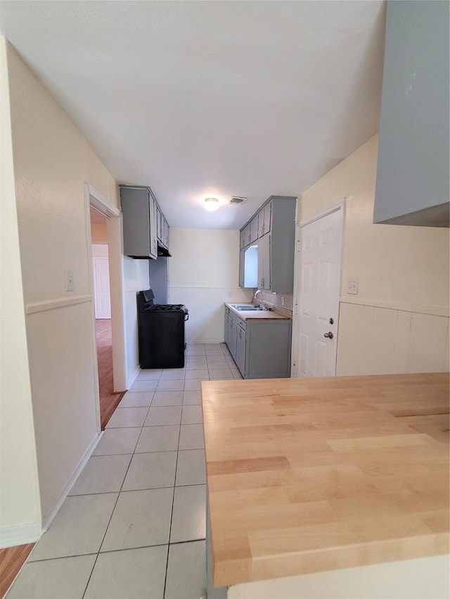 kitchen featuring gray cabinets, light tile patterned flooring, sink, and range with gas cooktop