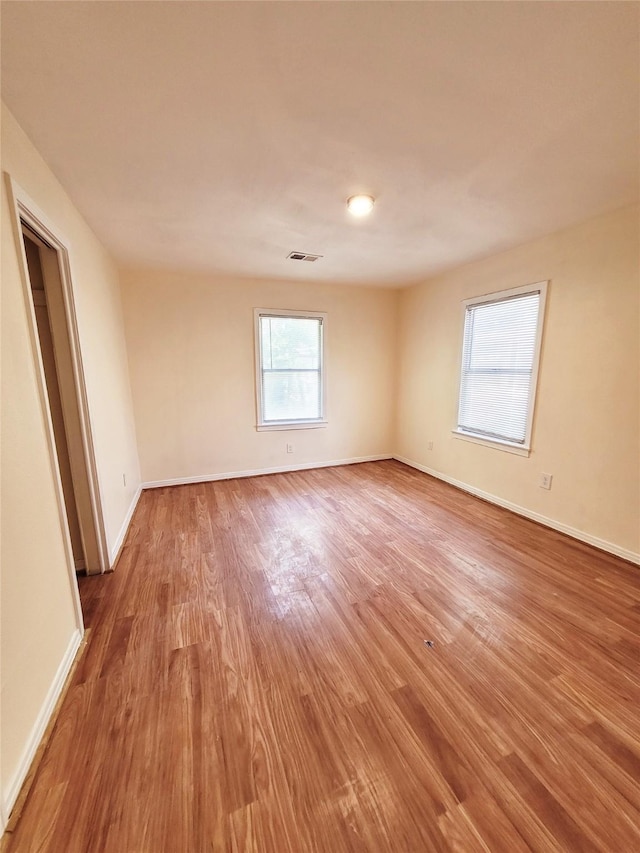 empty room with a wealth of natural light and hardwood / wood-style floors