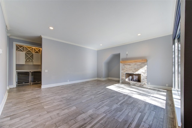 unfurnished living room featuring a stone fireplace, ornamental molding, and light wood-type flooring