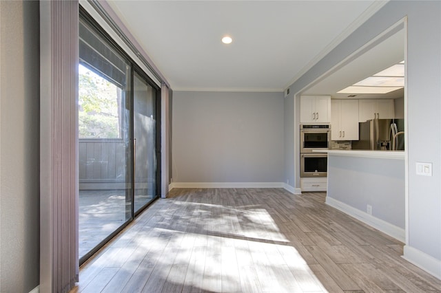 unfurnished living room with light hardwood / wood-style flooring and ornamental molding