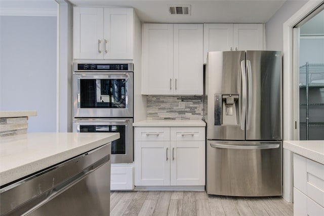 kitchen with light hardwood / wood-style floors, white cabinetry, stainless steel appliances, and tasteful backsplash