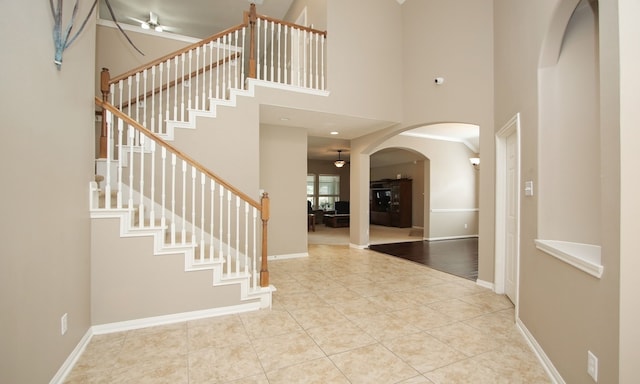 foyer entrance featuring ceiling fan, a towering ceiling, and light tile patterned floors