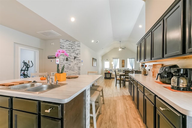 kitchen with a center island with sink, ceiling fan, lofted ceiling, and sink