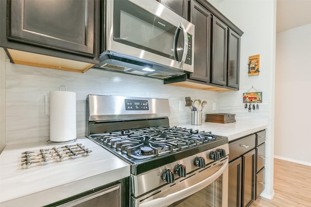 kitchen featuring backsplash, dark brown cabinets, light wood-type flooring, and stainless steel appliances