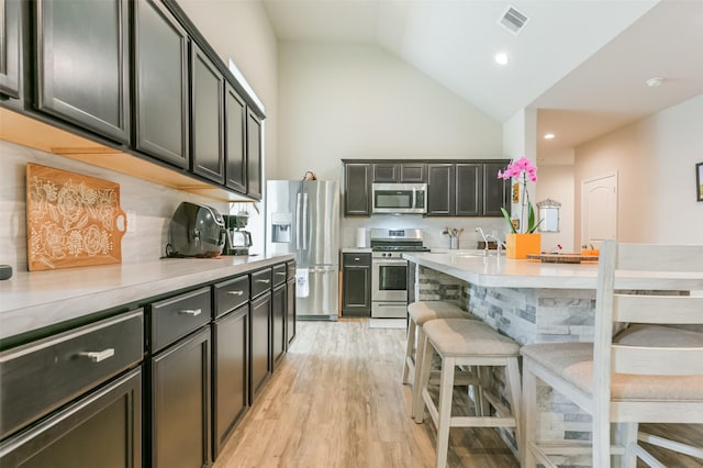 kitchen with sink, backsplash, a breakfast bar area, appliances with stainless steel finishes, and light wood-type flooring