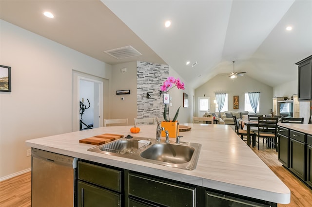 kitchen featuring ceiling fan, sink, dishwasher, lofted ceiling, and an island with sink