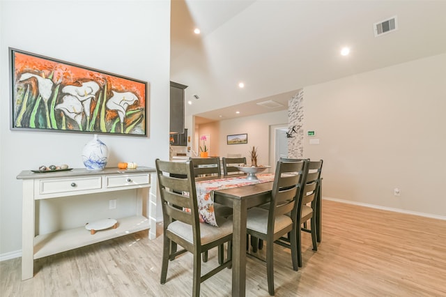 dining room with a towering ceiling and light hardwood / wood-style flooring