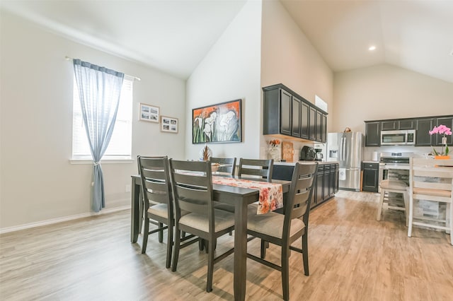 dining area featuring vaulted ceiling and light wood-type flooring