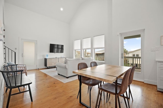 dining space with light hardwood / wood-style floors and high vaulted ceiling