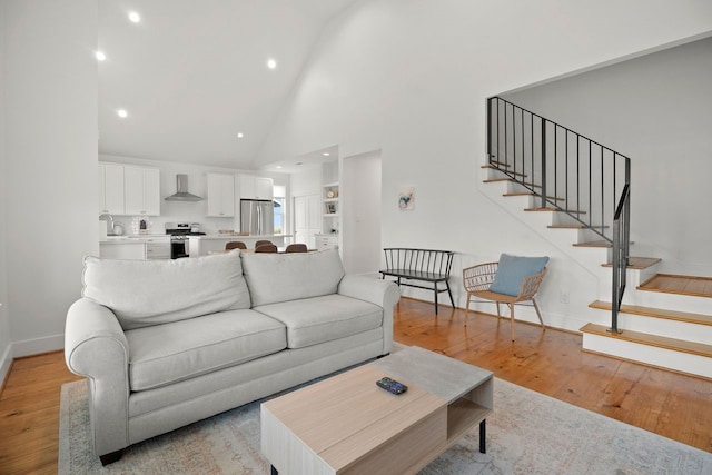 living room featuring high vaulted ceiling and light hardwood / wood-style flooring