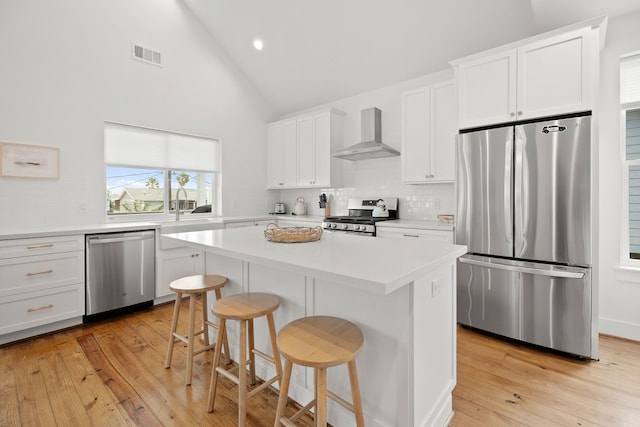 kitchen with wall chimney exhaust hood, a center island, white cabinetry, and stainless steel appliances