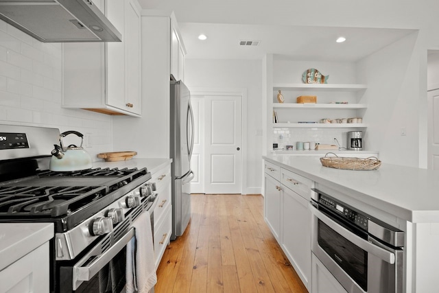 kitchen featuring exhaust hood, white cabinets, and stainless steel appliances