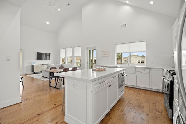 kitchen featuring white cabinets, plenty of natural light, appliances with stainless steel finishes, and high vaulted ceiling