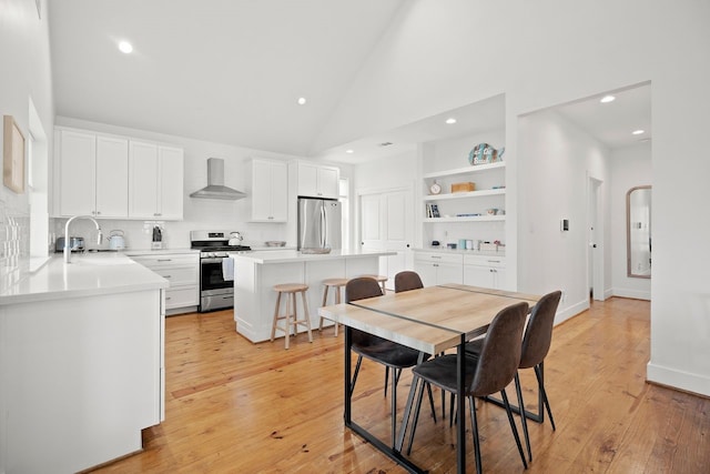 dining room featuring sink, high vaulted ceiling, built in features, and light wood-type flooring