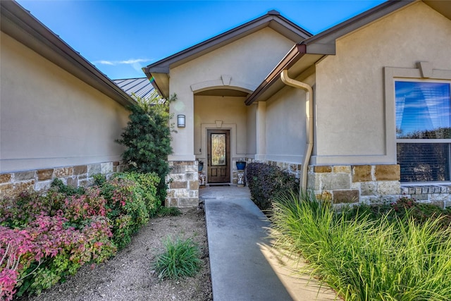 view of exterior entry featuring stone siding and stucco siding