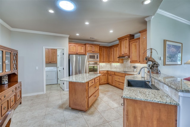 kitchen with washer / dryer, light stone counters, appliances with stainless steel finishes, and sink