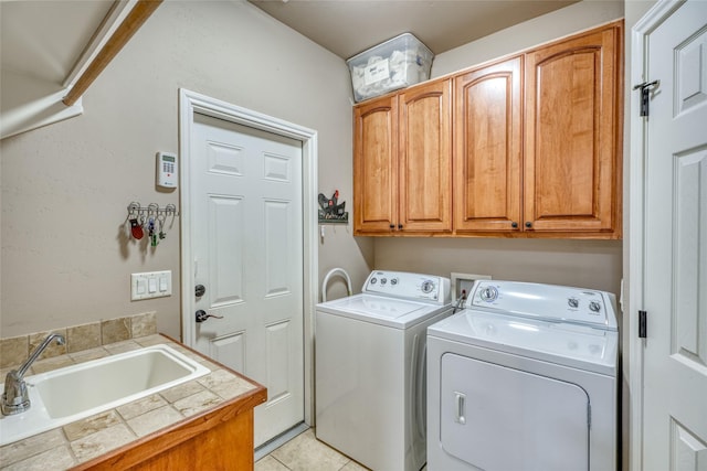 laundry area featuring light tile patterned flooring, cabinets, sink, and washing machine and dryer