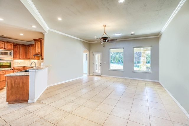 kitchen with visible vents, brown cabinets, backsplash, appliances with stainless steel finishes, and light stone countertops