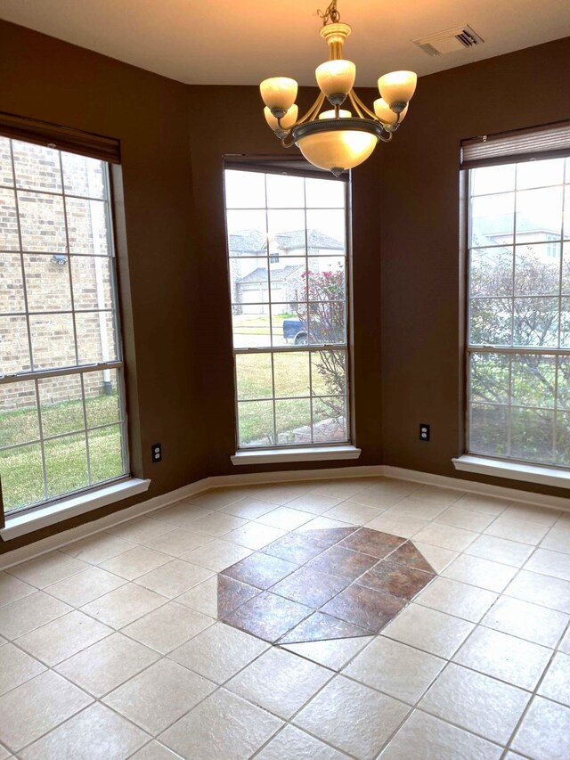 empty room with visible vents, a notable chandelier, baseboards, and light tile patterned floors