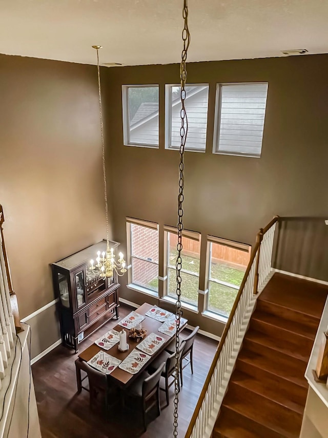 dining area featuring a high ceiling, baseboards, and wood finished floors