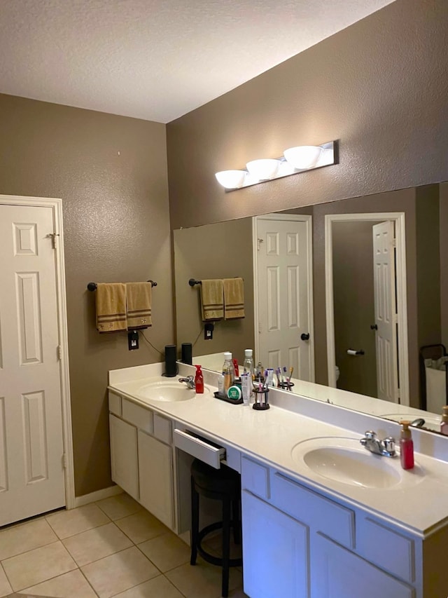 full bathroom with double vanity, tile patterned flooring, toilet, and a sink