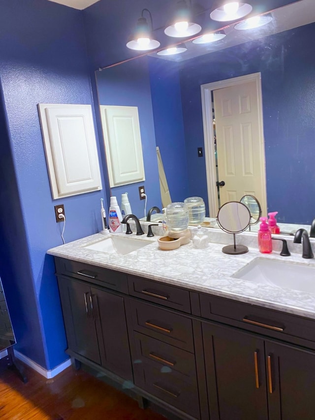 bathroom with double vanity, a sink, and wood finished floors