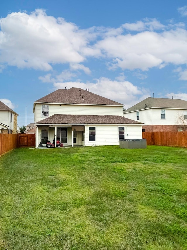 back of property with roof with shingles, a lawn, and a fenced backyard