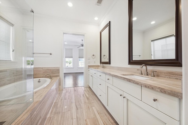 bathroom with ceiling fan, a relaxing tiled tub, crown molding, hardwood / wood-style floors, and vanity