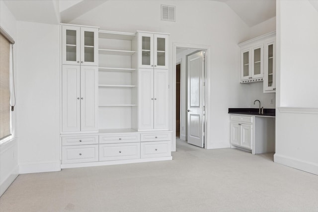 interior space with white cabinetry, vaulted ceiling, light colored carpet, and sink