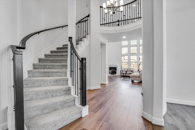 staircase featuring a high ceiling, hardwood / wood-style floors, and an inviting chandelier