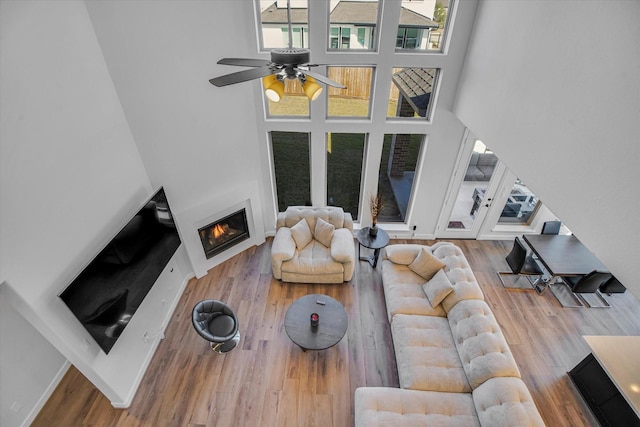 living room featuring a high ceiling, wood-type flooring, and ceiling fan