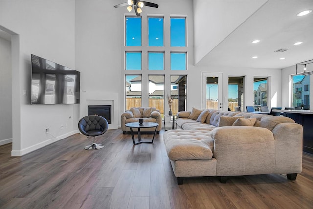 living room featuring a towering ceiling, dark wood-type flooring, and ceiling fan