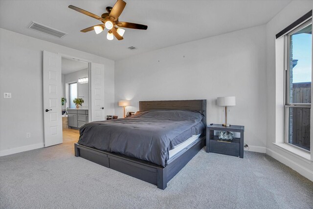 bedroom featuring ceiling fan, ensuite bath, and light carpet