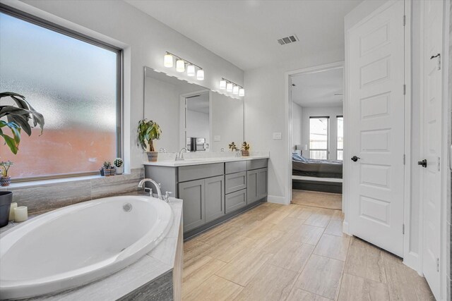 bathroom featuring vanity and tiled tub