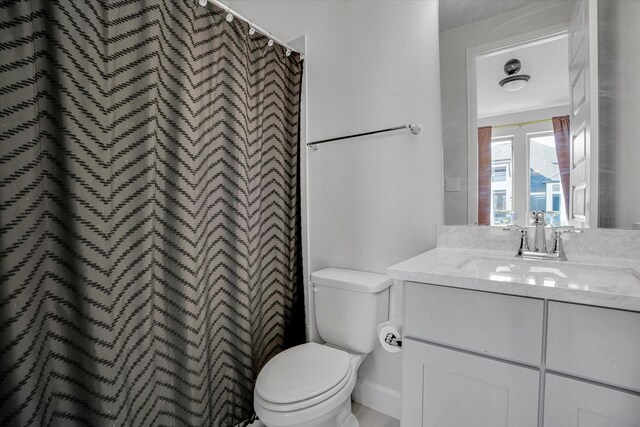 bathroom with curtained shower, vanity, and toilet