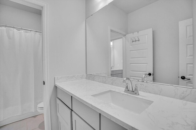 bathroom with toilet, tile patterned floors, and vanity