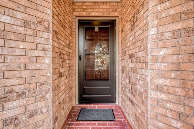 view of exterior entry featuring brick siding