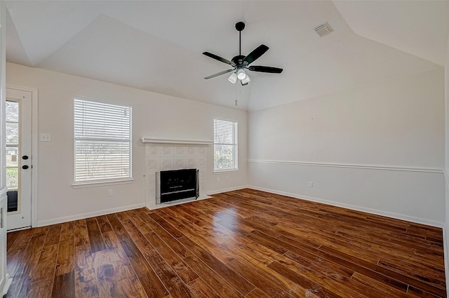 unfurnished living room with baseboards, visible vents, a tile fireplace, lofted ceiling, and wood finished floors