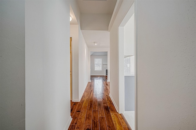 corridor with baseboards and wood finished floors