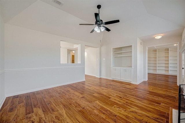 empty room featuring built in features, lofted ceiling, baseboards, and wood finished floors