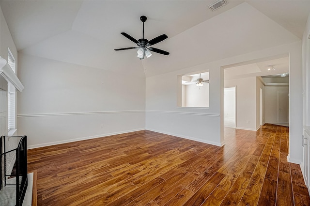 spare room with wood finished floors, a ceiling fan, visible vents, vaulted ceiling, and baseboards