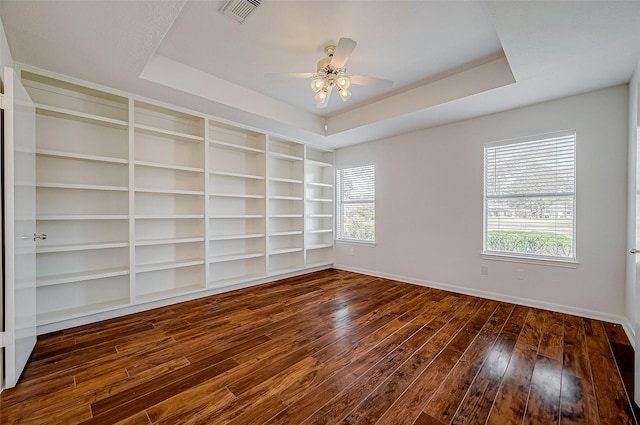 unfurnished room with a healthy amount of sunlight, hardwood / wood-style flooring, visible vents, and a tray ceiling