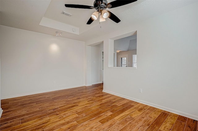 empty room featuring light wood-style floors, visible vents, baseboards, and a ceiling fan