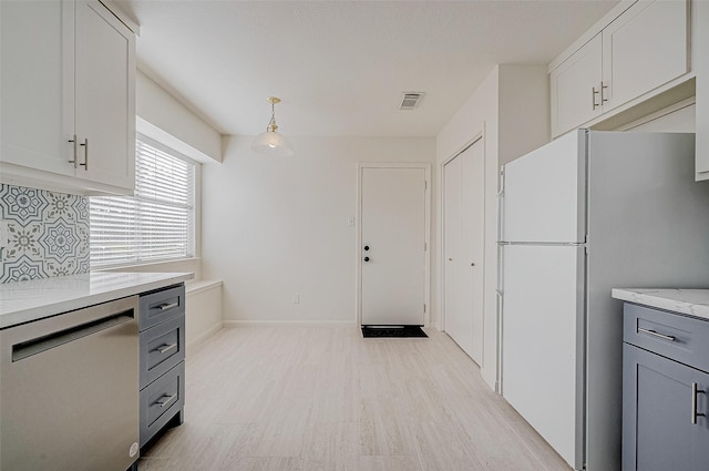 kitchen with tasteful backsplash, light wood-style flooring, freestanding refrigerator, gray cabinetry, and stainless steel dishwasher