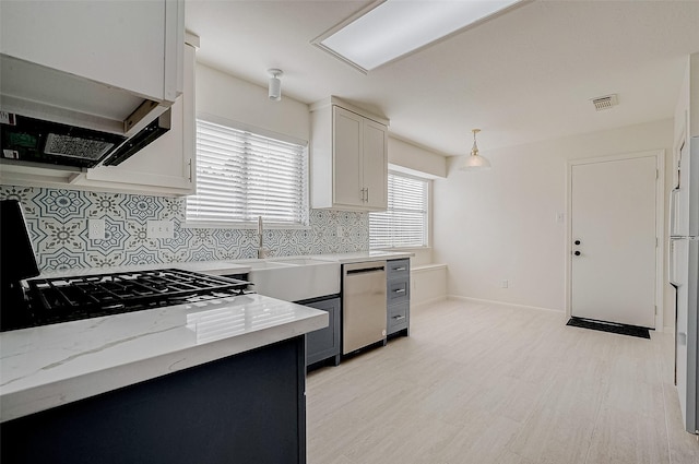 kitchen featuring visible vents, decorative backsplash, dishwasher, white cabinetry, and a sink