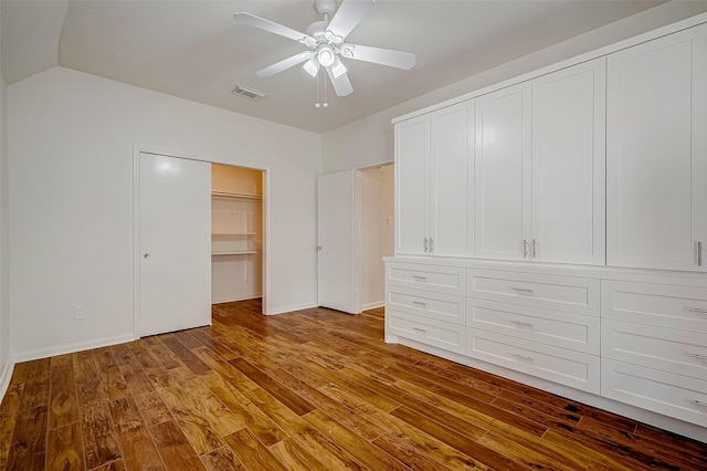 unfurnished bedroom featuring visible vents, vaulted ceiling, ceiling fan, wood finished floors, and baseboards