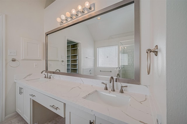 bathroom featuring vaulted ceiling, double vanity, a stall shower, and a sink