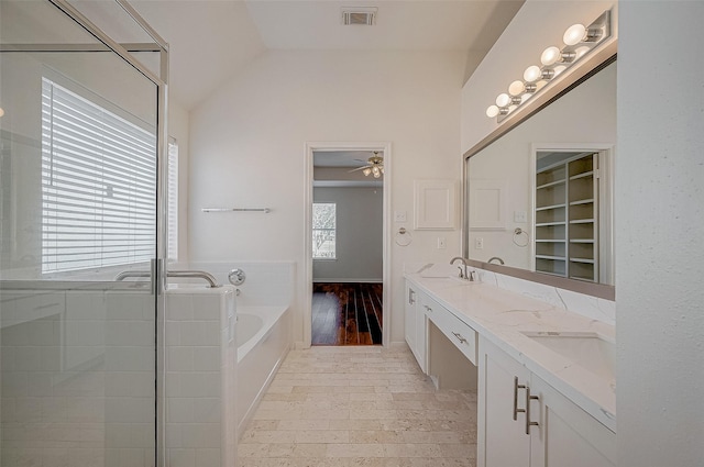 bathroom with a garden tub, double vanity, lofted ceiling, visible vents, and a sink