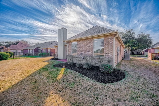 view of property exterior with a chimney, fence, cooling unit, a yard, and brick siding