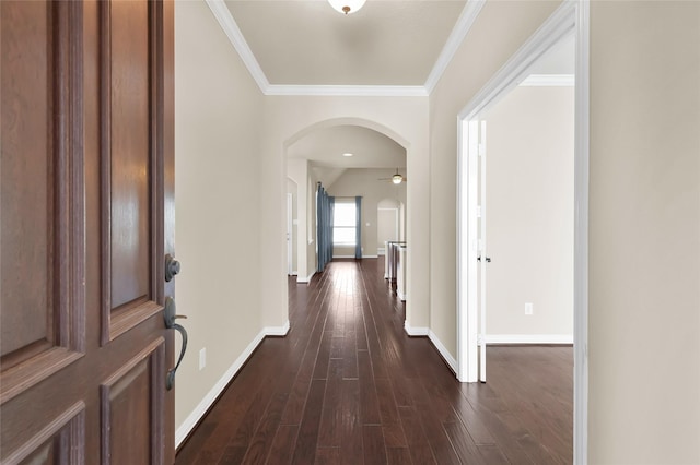 interior space featuring dark wood-style floors, baseboards, arched walkways, and ornamental molding